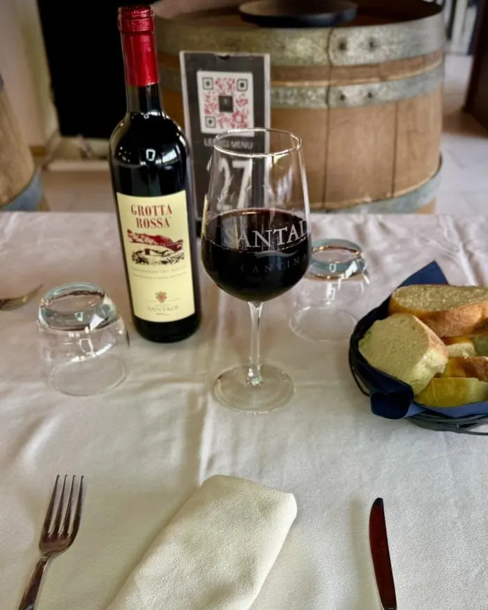 Una bottiglia di Grotta Rossa e un calice di vino rosso sulla tovaglia